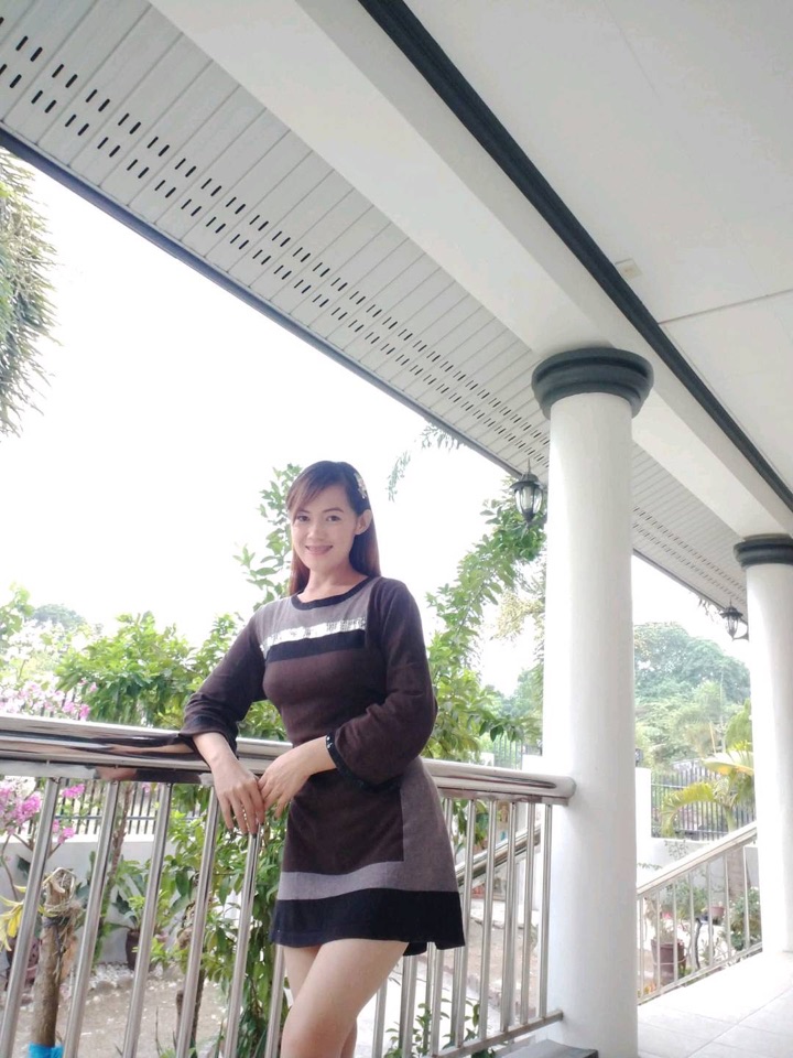 Adult wearing a dark long-sleeve dress on a bright veranda